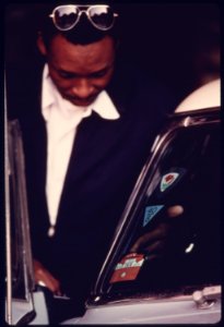 City Employee Affixes a 1976 Inspection Seal to the Windshield of a Car That Has Successfully Passed Testing at an Auto Emission Inspection Station in Downtown Cincinnati, Ohio...09-1975 (4265797199)