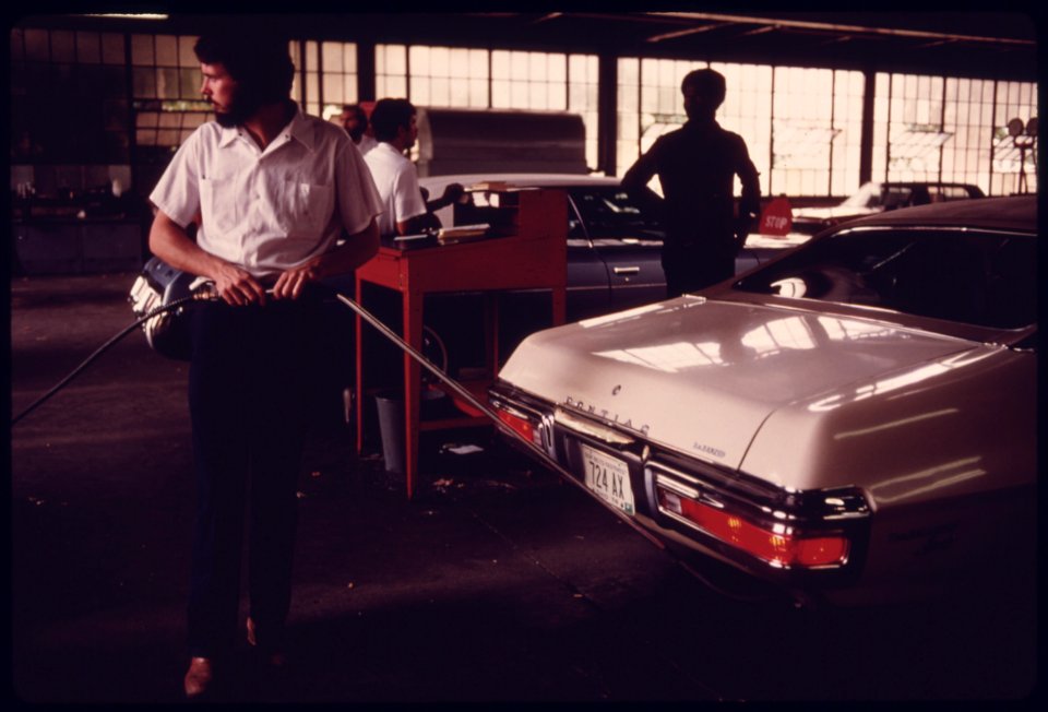 City Employee of an Auto Emission Inspection Station in Downtown Cincinnati, Ohio, Holds a Probe Attached to the Tailpipe of a Car...08-1975 (4265790031)