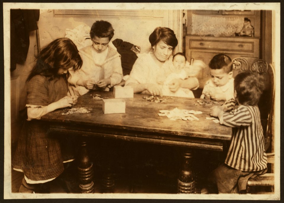 Civarro family, 2106 Second Avenue, second floor back, working on patriotic flag pins. They get 3 cents a gross for inserting pin and putting onto card. Mrs. Civarro with her three-months-old baby in LOC nclc.04316