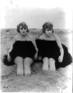 Claire Anderson and Rose Carter (seated on beach, draped in a fur, with feet in sand) LCCN2002711770