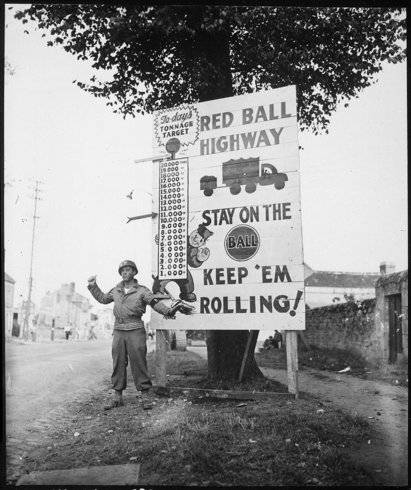 Corporal Charles H. Johnson of the 783rd Military Police Battalion, waves on a Red Ball Express motor convoy... - NARA - 531220
