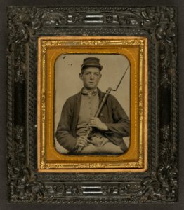 Corporal John A. Hartshorn of Company A, 19th Maine Infantry, in Union uniform sitting with bayoneted musket) - From Walton's Ambrotype & Photograph Rooms, corner of Merrimack and Pecker LCCN2010648796