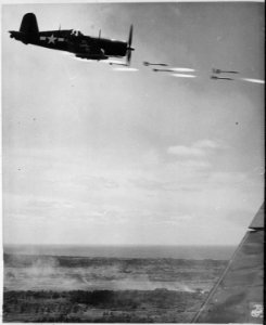 Corsair fighter looses its load of rocket projectiles on a run against a Japanese stronghold on Okinawa. In the lower... - NARA - 532377 photo