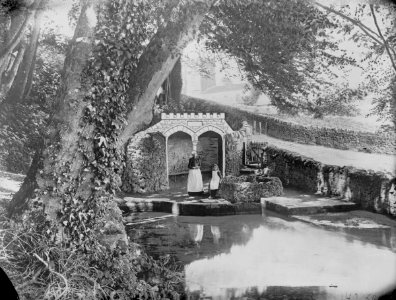 Country scene with a woman and girl by a well and a man-made pond. (4641621)