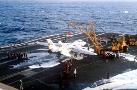 Crane lifts damaged F-14A of VF-1 on USS Kitty Hawk (CV-63) in 1984