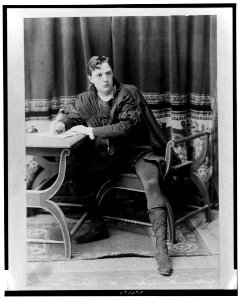 Creston Clarke, full-length portrait, facing slightly right, seated at desk, writing with quill pen, as a character in a play LCCN2001700498