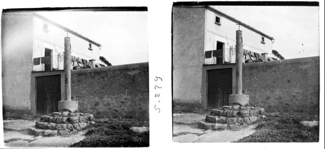 Creu de terme al costat d'una casa