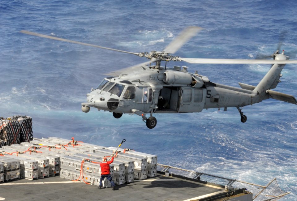 Crew member attaches cargo to a Sea Hawk at sea. (8692079213)