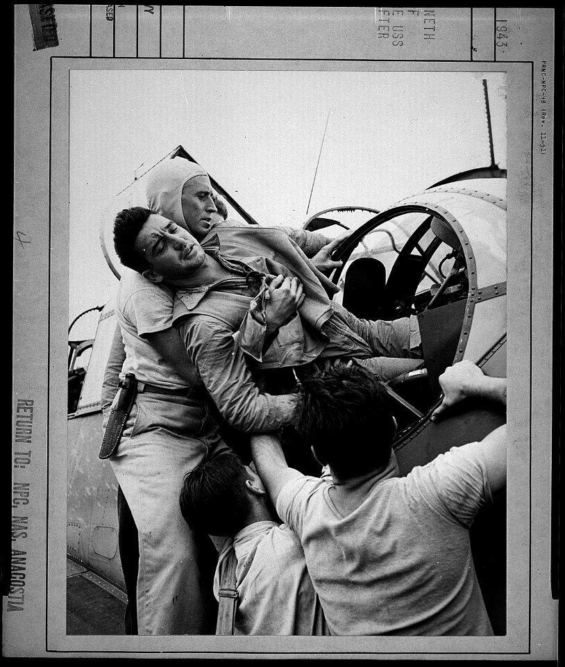 Crewmen lifting Kenneth Bratton (AOM) out of turret of TBF on the USS Saratoga (CVA-3) after raid on Rabaul. - NARA - 520757