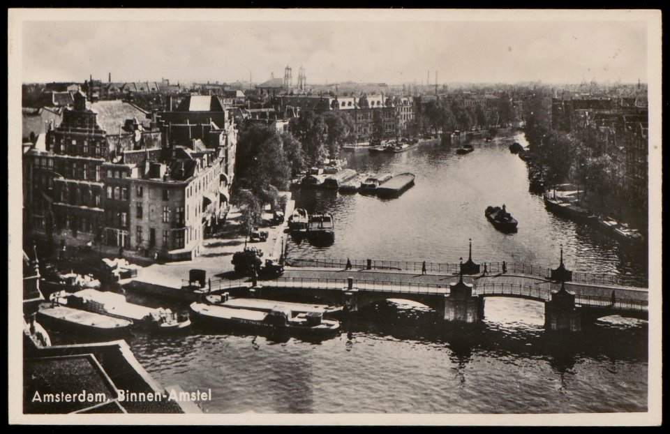 De Halvemaansbrug in de Binnen Amstel met rechts de even zijde van de Amstel en links Kloveniersburgwal hoek 's Gravenlandse Veer. Op de achtergrond de Mozes en Aäronkerk . Uitgave J. Sleding, Afb PBKD00244000001