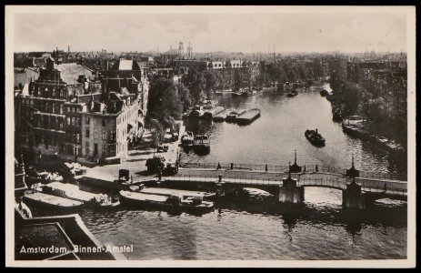 De Halvemaansbrug in de Binnen Amstel met rechts de even zijde van de Amstel en links Kloveniersburgwal hoek 's Gravenlandse Veer. Op de achtergrond de Mozes en Aäronkerk . Uitgave J. Sleding, Afb PBKD00244000001