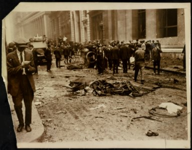 Crowd gathered behind a dead horse after the Wall Street explosion in front of the offices of J.P. Morgan; man, probably a reporter, writes in a notebook in the foreground LCCN2015645596