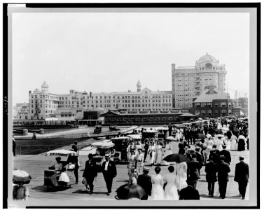 Crowd of people and wheeled chairs on boardwalk; Hotel Traymore in background, Atlantic City, New Jersey LCCN98505463
