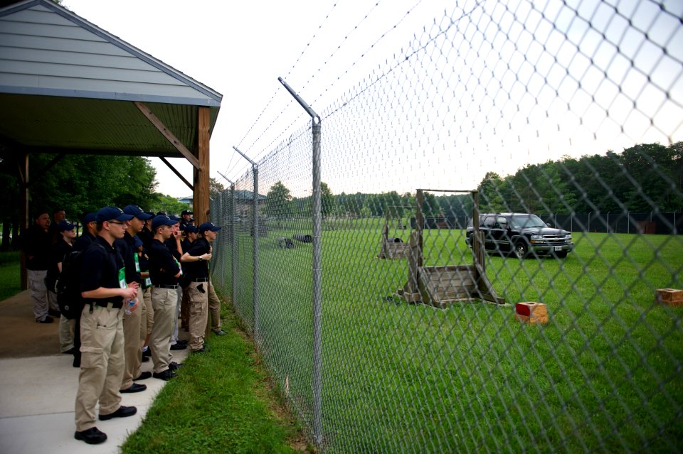 Crowd of law enforcement explorers stare through a fence
