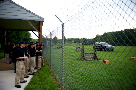 Crowd of law enforcement explorers stare through a fence photo