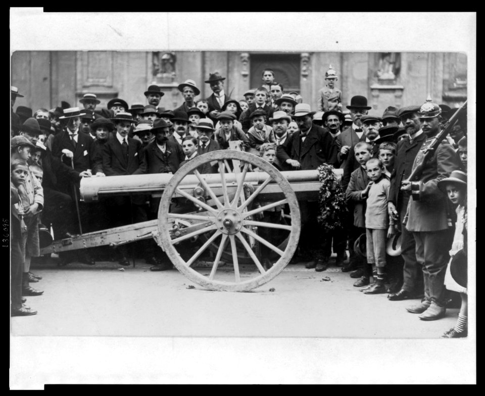 Crowd of German civilians, including children, surrounding a cannon which has a garland hanging from the muzzle LCCN2005697192