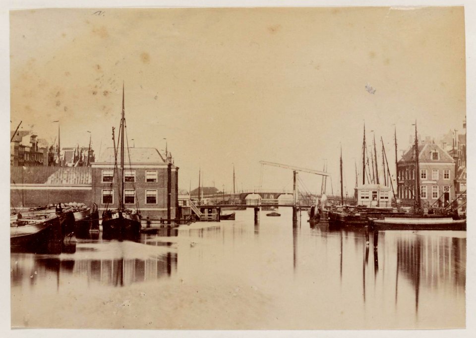 Damrak-Met o.a. Korenbeurs (links) en de oude brug (voorgrond) en de Nieuwe Brug (achtergrond)