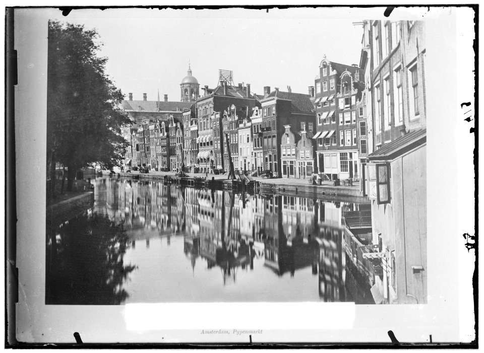 De Pijpenmarkt (Nieuwezijds Voorburgwal) gezien in noordelijke richting naar de Dam. Op nummer 187-189 het pand van stoomdrukkerij Roeloffzen-Hübner en Van Santen, gebouwd in 1875