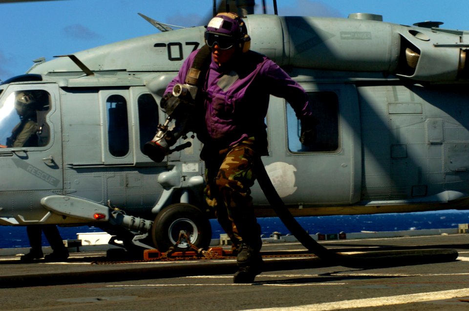 Defense.gov News Photo 100719-N-6477M-407 - U.S. Navy Airman Carlos Gomez retrieves fuel lines after refueling an HS-60 Seahawk helicopter on the flight deck of the amphibious transport dock