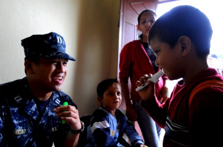 Defense.gov News Photo 100719-N-9643W-1219 - U.S. Navy Lt. Michael Quisao left plays the kazoo with a student from Escuela de Las Pampas during a community relations event with U.S. sailors