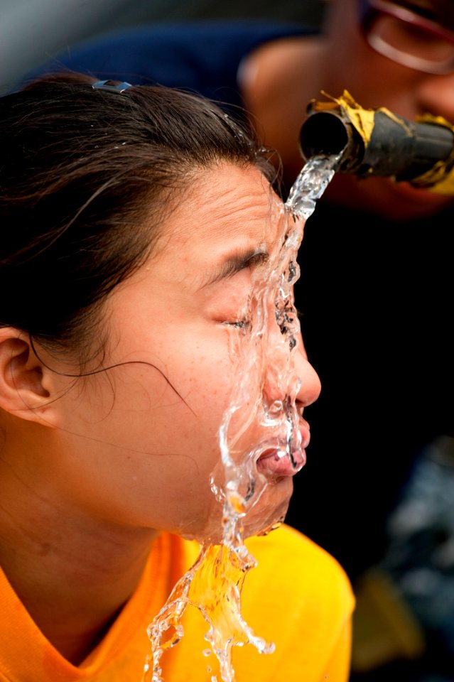Defense.gov News Photo 100814-N-5319A-059 - U.S. Navy Petty Officer 2nd Class Tara Passmore runs water over the head of Ensign Jessica Alabata as sailors from the amphibious assault ship USS