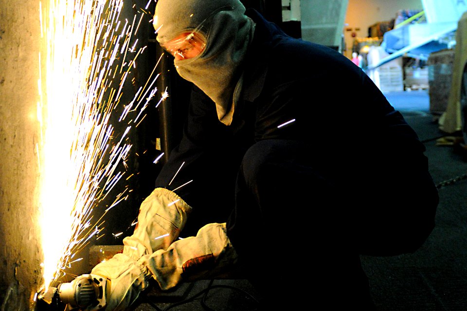 Defense.gov News Photo 101220-N-8040H-059 - U.S. Navy Seaman Anthony Fleeman grinds off safety hazards in the hangar bay aboard the aircraft carrier USS Carl Vinson in the Pacific Ocean on