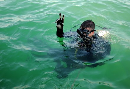 Defense.gov News Photo 101229-N-0413B-083 - U.S. Navy Senior Chief Joseph Pendino assigned to Mobile Diving and Salvage Unit 2 signals before diving under water while conducting an