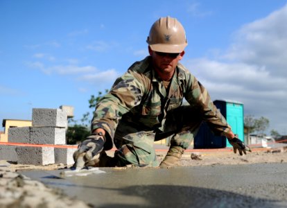 Defense.gov News Photo 110111-N-2984R-363 - U.S. Navy Petty Officer 2nd Class Andras Toth assigned to Naval Mobile Construction Battalion 28 trowels the foundation of a new classroom being photo