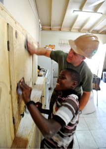 Defense.gov News Photo 110417-N-NY820-518 - Sgt. Peter Swigart and a local child sand newly built cabinets at Trenchtown Primary School in Kingston Jamaica during a Continuing Promise 2011