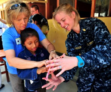 Defense.gov News Photo 110503-N-QD416-114 - Sheryl Flanary left and U.S. Navy Lt. j.g. Sara Edmonson right teach a patient how to play a game at a medical clinic set up by the staff of the