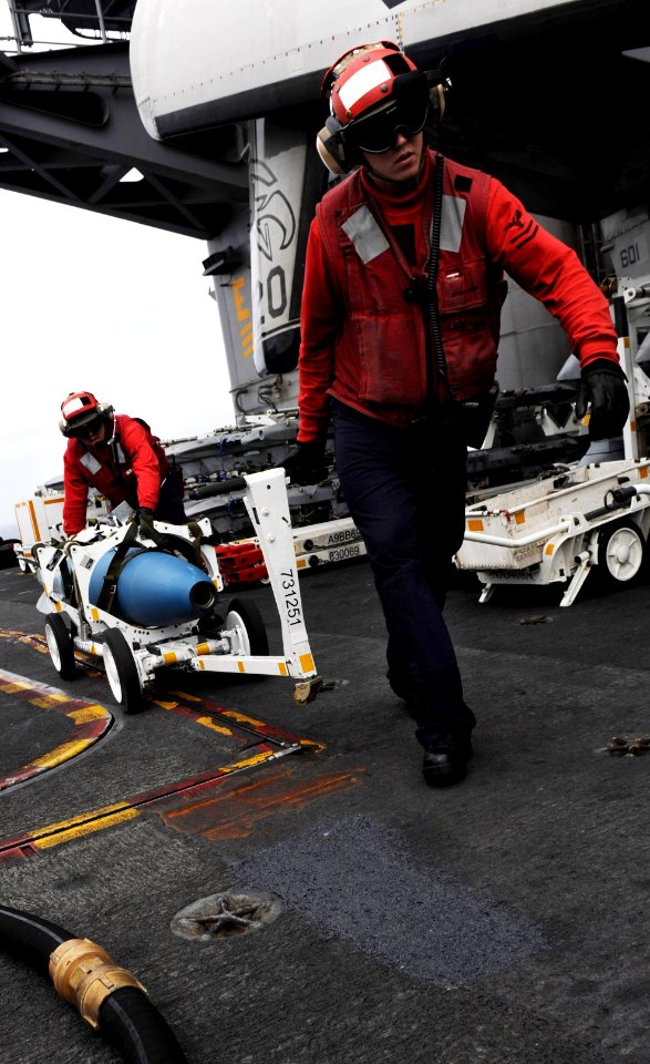 Defense.gov News Photo 110513-N-OY799-122 - Petty Officer 2nd Class Jeffrey Anderson right and Petty Officer 1st Class Michael Washa move ordnance on the flight deck of the aircraft carrier