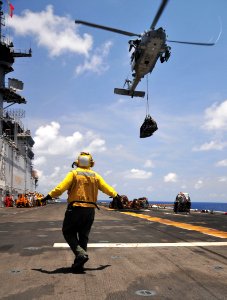 Defense.gov News Photo 110519-N-ZS026-132 - U.S. Navy Petty Officer 3rd Class Rodolfo Lopez signals an MH-60 Seahawk helicopter with Helicopter Sea Combat Squadron 23 to lower a pallet of photo