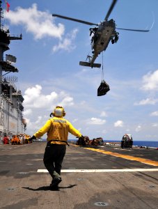 Defense.gov News Photo 110519-N-ZS026-132 - U.S. Navy Petty Officer 3rd Class Rodolfo Lopez signals an MH-60 Seahawk helicopter with Helicopter Sea Combat Squadron 23 to lower a pallet of