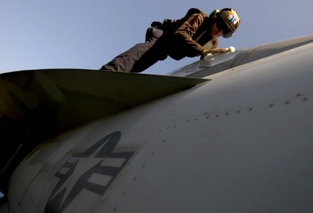 Defense.gov News Photo 110423-N-GZ277-024 - U.S. Navy Seaman Bryan Domingue assigned to Strike Fighter Squadron 22 cleans the canopy on an F A-18F Super Hornet aircraft aboard the aircraft
