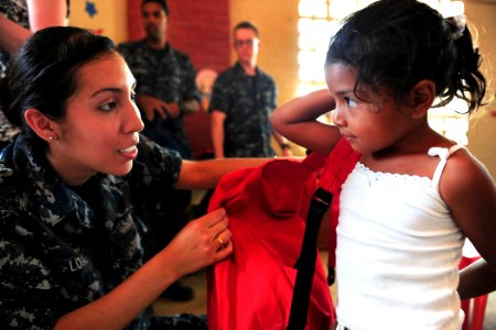 Defense.gov News Photo 110520-N-QD416-443 - U.S. Navy Seaman Arianna Loaiza helps a student put on a donated backpack during a Continuing Promise 2011 community service event in Santa Rosa photo