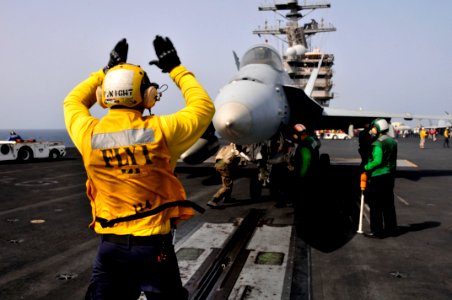 Defense.gov News Photo 110606-N-AV746-450 - Petty Officer 3rd Class Patrick Wight signals to the pilots of an F A-18 aircraft before launching off the flight deck of the aircraft carrier USS
