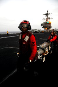 Defense.gov News Photo 110718-N-JE719-838 - Petty Officer 3rd Class Damion Ferguson left and Petty Officer 2nd Class Christopher Bowman transport ordnance on the flight deck of the aircraft