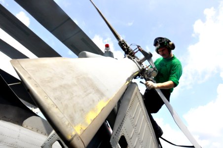 Defense.gov News Photo 110809-N-ZZ999-018 - U.S. Navy Petty Officer 2nd Class Branden Rucker performs maintenance to control corrosion on the tail rotor of an SH-60F Seahawk helicopter
