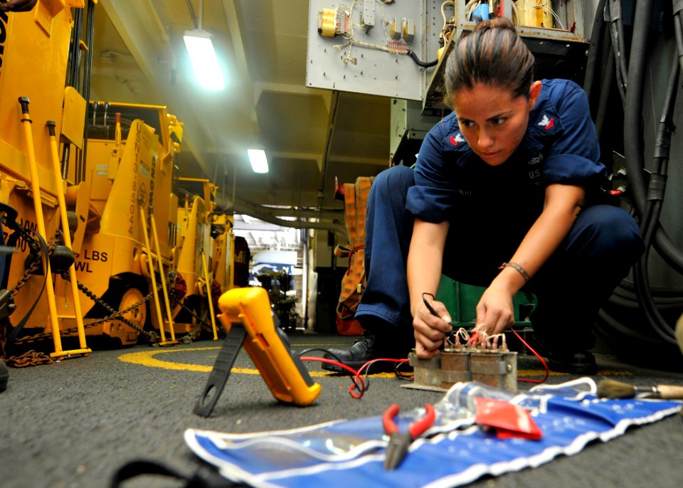 Defense.gov News Photo 110723-N-EE987-125 - Petty Officer 2nd Class Maria Arreedondo uses a flow divider while fixing a forklift battery charging station in the hangar bay of the aircraft