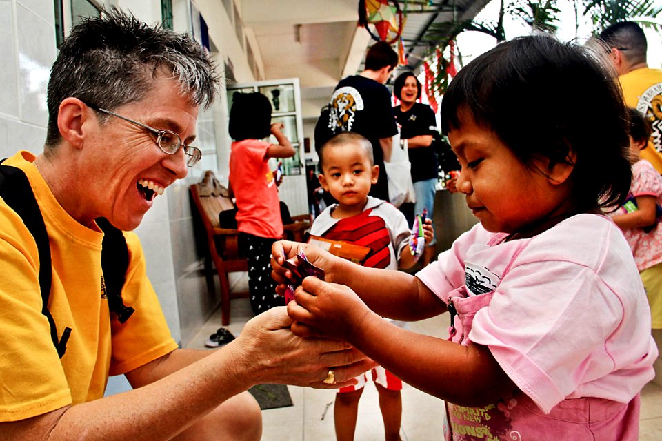Defense.gov News Photo 120107-N-1261P-001 - U.S. Navy Master Chief Petty Officer Susan Whitman shares candy with a young girl during a community service project at the Camillian Social Center
