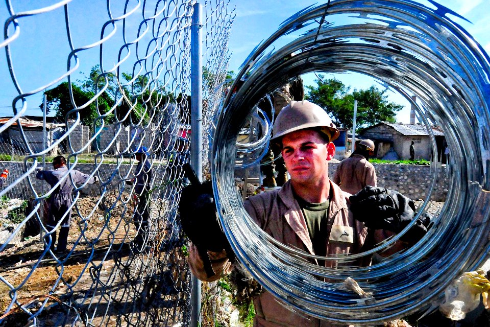 Defense.gov News Photo 110820-N-VV618-180 - U.S. Marine Corps Lance Cpl. Steven Cole unravels razor wire at the Esaie Jeanty Hospital Cite Soleil engineering site during Continuing Promise
