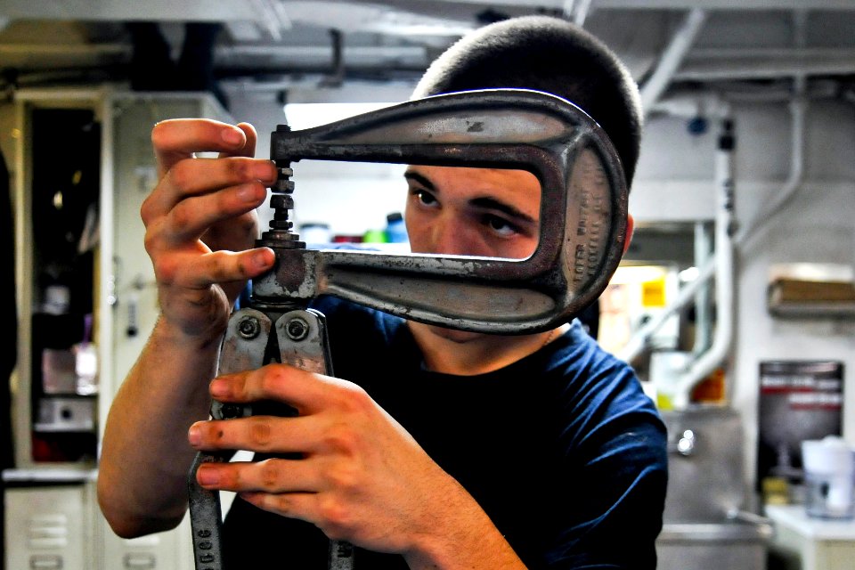 Defense.gov News Photo 120110-N-ZZ999-401 - U.S. Navy Seaman Kaleb White adjusts a rivet squeezer while repairing a damage bucket aboard the aircraft carrier USS Carl Vinson CVN 70 in the