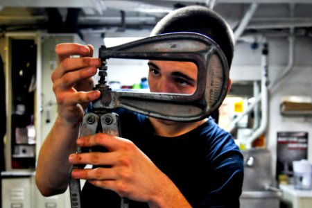 Defense.gov News Photo 120110-N-ZZ999-401 - U.S. Navy Seaman Kaleb White adjusts a rivet squeezer while repairing a damage bucket aboard the aircraft carrier USS Carl Vinson CVN 70 in the