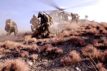 Defense.gov News Photo 120225-N-BV659-316 - U.S. Special Operations personnel take cover to avoid flying debris as they prepare to board a UH-60 Black Hawk helicopter during a mission in