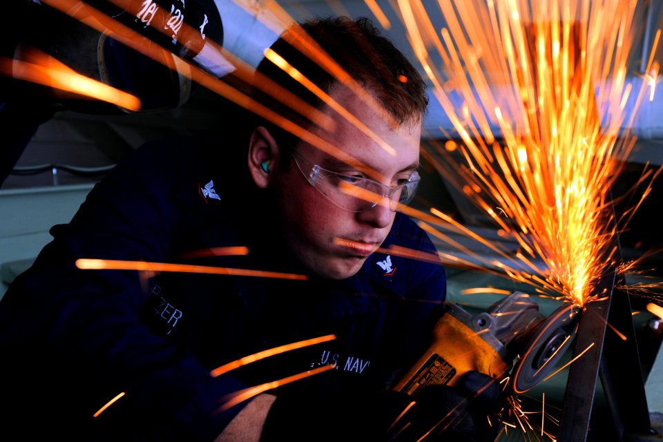 Defense.gov News Photo 111206-N-EK905-066 - U.S. Navy Petty Officer 3rd Class Nicholas Pitzer grinds the frame of a table in the recreation room aboard the amphibious assault ship USS Makin