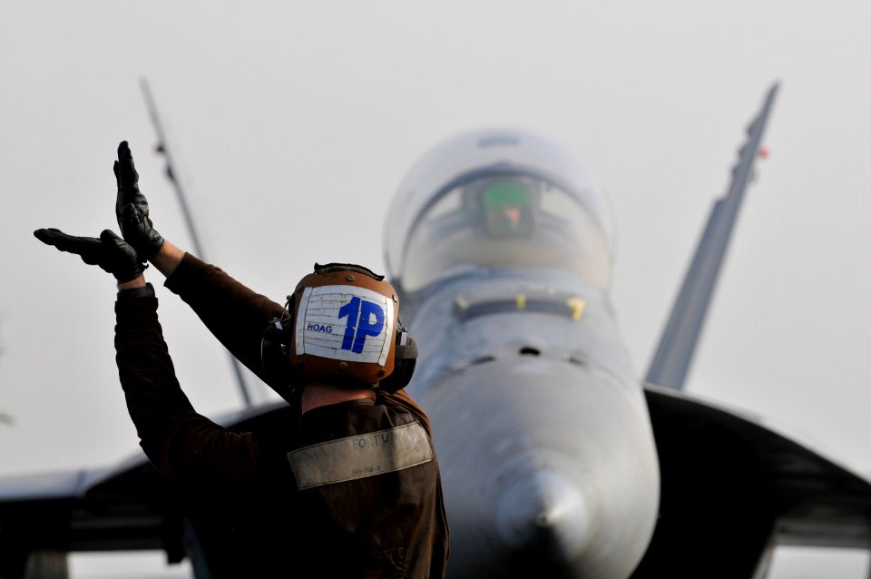 Defense.gov News Photo 120305-N-ZI635-382 - U.S. Navy Airman Mackenzie Hoag assigned to Strike Fighter Squadron 22 signals to the pilot of an F A-18F Super Hornet aircraft aboard the