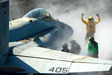 Defense.gov News Photo 120305-N-DR144-458 - U.S. Navy Petty Officer 3rd Class Eric Welsh directs an F A-18C Hornet onto the bow catapults for launch on the flight deck aboard the aircraft