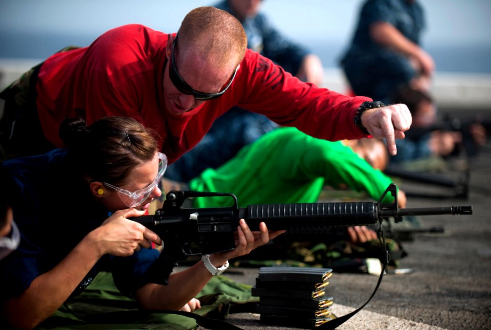 Defense.gov News Photo 120308-N-PB383-515 - Petty Officer 1st Class Allen Lunn a line coach gives Seaman Brittany Koval instruction on how to fire an M-16 service rifle during a live-fire