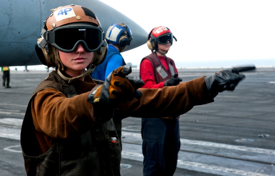 Defense.gov News Photo 120109-N-OY799-024 - U.S. Navy Airman Elaine Ketola left signals for the start up of an F A-18C Hornet aircraft from Strike Fighter Squadron 192 on the flight deck of