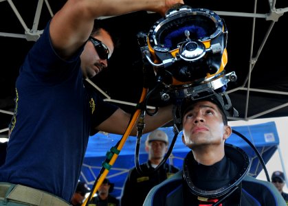 Defense.gov News Photo 120301-N-ZX920-475 - U.S. Navy Petty Officer 3rd Class Richard Burby assigned to Mobile Diving and Salvage Unit 2 Company 2-1 places a KM 37 dive helmet onto